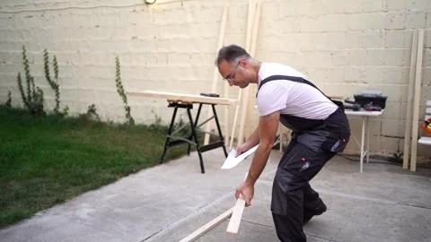 Creating a wooden structure in the backyard with expert craftsmanship on a sunny Stock Footage 303828095