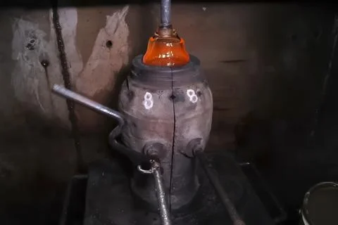 Creation of glass vessels by method of molded blowing of hot glass. Stock Photos