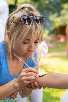 Creative activity at children celebration with a young woman painting on a bo Stock Photos