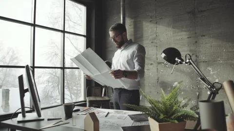 Creative architect thinking on big drawings, standing faces to window Stock Photos