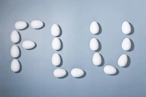 Creative arrangement of white eggs spells out flu on a blue background, Stock Photos