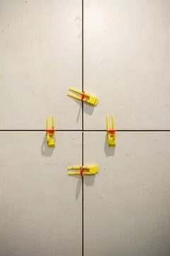 Creative Arrangement of Yellow Clips Securing Tiles in a Neutral-Toned Space Stock Photos