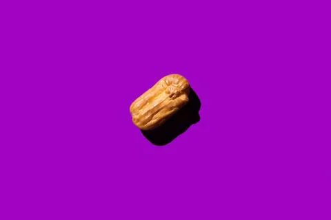 Creative art with yellow Eclair on purple background. flat lay Stock-Fotos