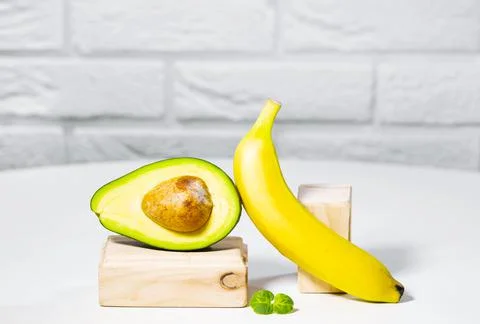 Creative avocado, banana and micro green balance wooden stands and podiums Stock Photos