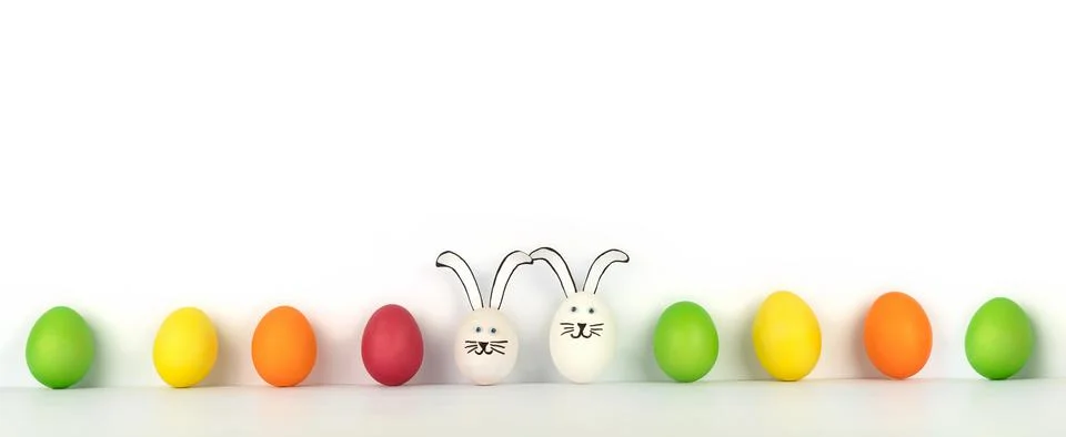 Creative banner from multi-colored eggs in row and two funny rabbits. White b Фото