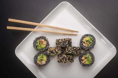 Creative Black Sushi Roll Presentation with Chopsticks on White Plate Stock Photos