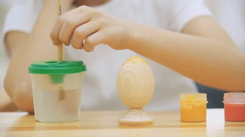 Creative boy is painting an Easter egg in an yellow colour with a help of paint Stock Footage 104639768