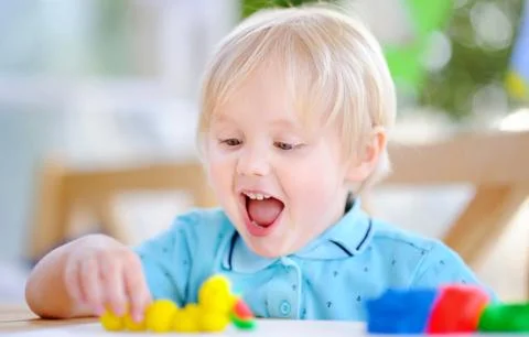 Creative boy playing with colorful modeling clay at kindergarten Foto stock