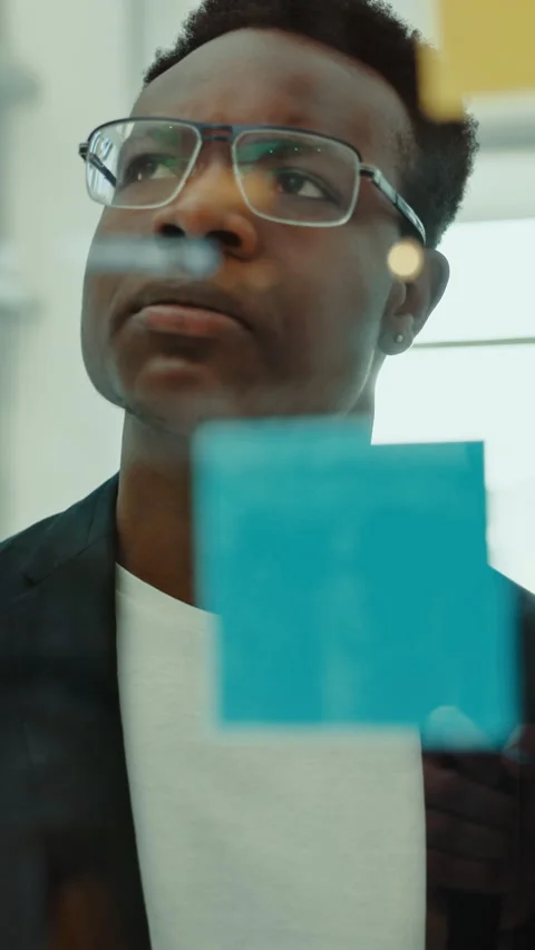 Creative, brainstorming and black man at glass wall with sticky note, thinking Stock Footage 332890580