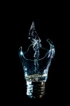 Creative broken light bulb with water fountain on isolated black background w Stock Photos
