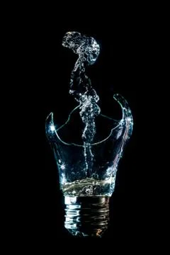 Creative broken light bulb with water fountain on isolated black background w Stock Photos