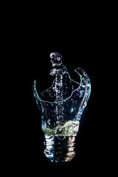 Creative broken light bulb with water fountain on isolated black background w Stock Photos