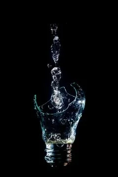 Creative broken light bulb with water fountain on isolated black background w Stock Photos