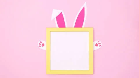 Creative bunny ears and paws appear under copy space frame. flat lay stop motion Vídeo Stock 149916650