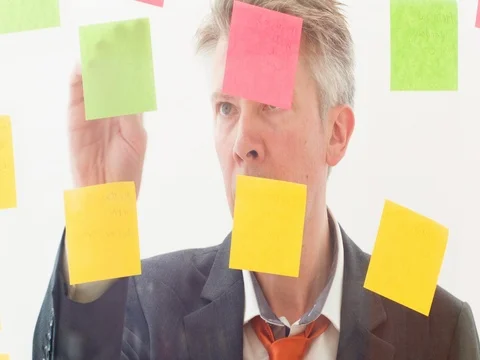 Creative businessman putting post it notes on to a window Stock Footage 80171659