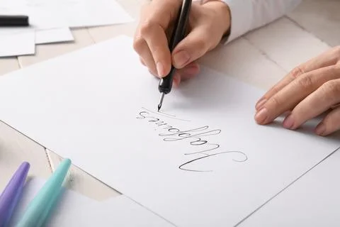 Creative calligraphy writing process with dip pen on white paper, artistic ha Stock Photos