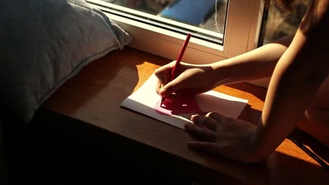 Creative child immersed in drawing sitting by window at home. Drawing hobby Stock Footage 309525799