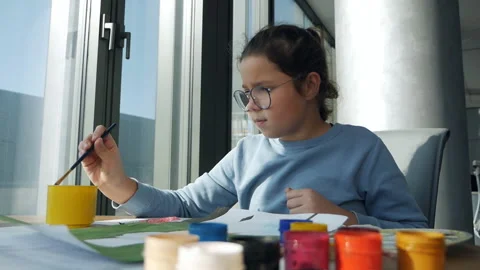 Creative child learns to draw on paper. A little girl sitting at the table draws Stock Footage 163842040