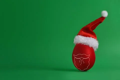 Creative christmas. Composition of a red egg with painted beard in a Santa hat. Stock Photos