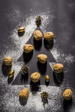 Creative Christmas flat lay with nuts, pinecones, and gold decorations arrang Stock Photos