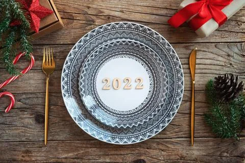 Creative Christmas table setting. Empty plates, numbers 2022, on rustic wooden Stock Photos