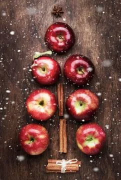 Creative Christmas tree made from red apples, cinnamon and anise star on wood Stock Photos