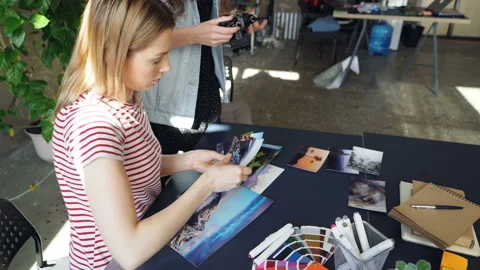 Creative colleagues placing pictures on table and shooting flat lay while Stock Footage 88729834