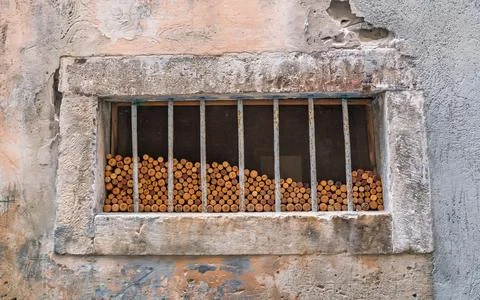 A creative collection of used wine corks fills an old barred window, set in a Stock Photos