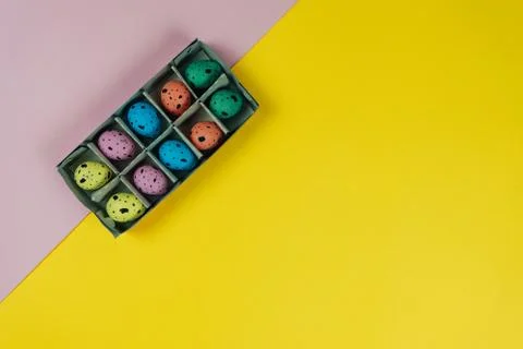 Creative colorful Easter quail eggs in carton box isolated on yellow and pink Stock Photos