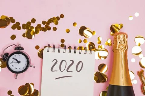 Creative composition with clock, golden confetti and notepad with text 2020. Stock Photos