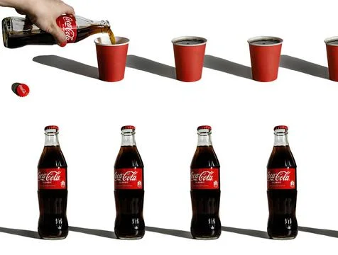 Creative composition with coca-cola repeated bottles and paper glasses Stock Photos