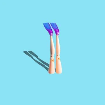 Creative composition with doll legs and flippers on blue background. Stock Photos