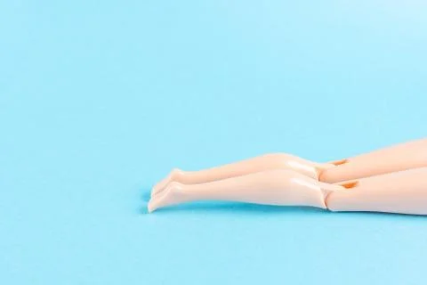 Creative composition with doll legs on blue background. Stock Photos