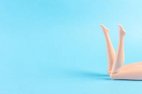 Creative composition with doll legs on blue background. Stock Photos