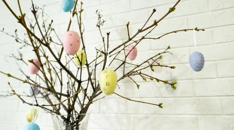 Creative composition with Easter eggs hanging on tree branches near a white Фото