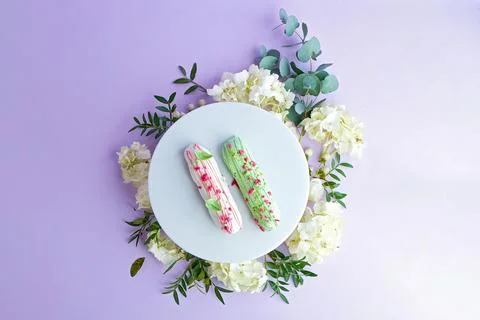 Creative composition with flowers and eclairs on a pink background Foto stock