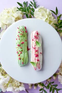 Creative composition with flowers and eclairs on a pink background Stock Photos