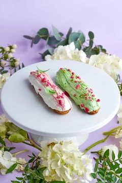 Creative composition with flowers and eclairs on a pink background Stock Photos