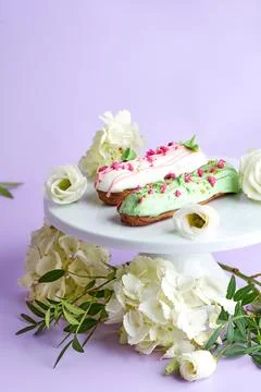 Creative composition with flowers and eclairs on a pink background Stock Photos