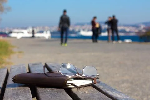Creative composition with leather Notepad and Glasses on wood bench seafront Stock Photos