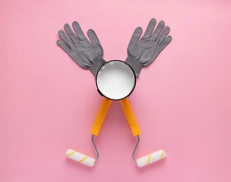 Creative composition of paint rollers, open can of white paint, and work glov Stock Photos