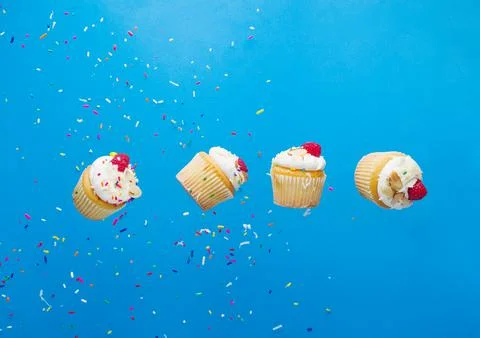 Creative composition. Small muffins with cream and fresh raspberries on a bri Stock Photos