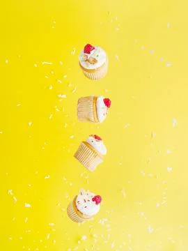 Creative composition. Small muffins with cream and raspberries on a bright ye Stock Photos