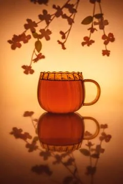 Creative composition still life with transparent mug and tea, with flower i.. Stock Photos