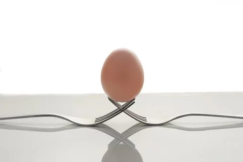 Creative composition of two forks and an egg isolated on a white background Stock Photos