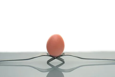 Creative composition of two forks and an egg isolated on a white background Stock Photos