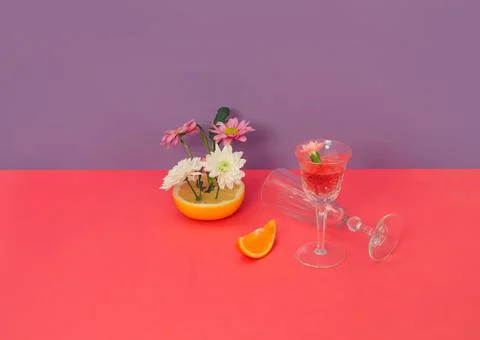 Creative composition of white and lilac daisy flowers, fruits, and glasses Stock Photos