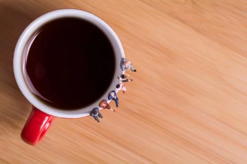 Creative concept about drinking coffee and waiting. People sit on a cup Stock Photos