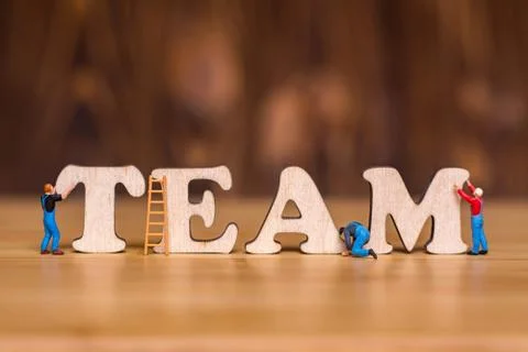 Creative concept about teamwork. Miniature people and wooden letters TEAM Stock Photos