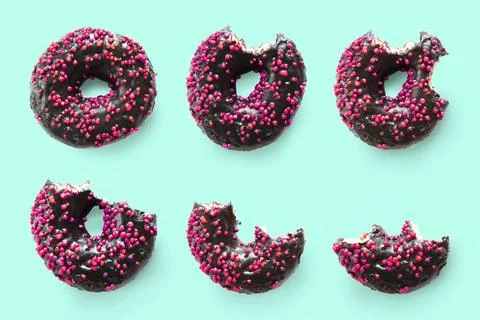 Creative concept of biting eating delicious sweet sugar black doughnut donu.. Stock Photos